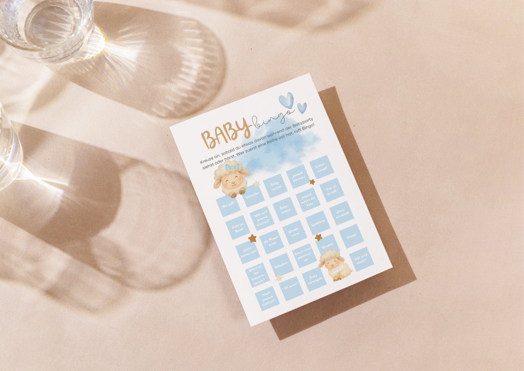 Baby Bingo Karte für Babyparty im Boho Stil, blaues Design mit Lammmotiv auf hellem Tisch mit Glasreflexen