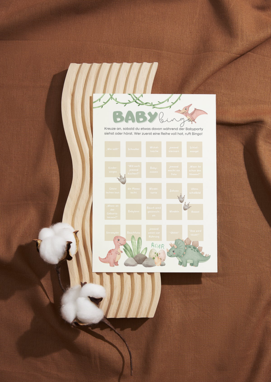 Boho Baby Bingo Spielkarte mit Dino-Motiv auf braunem Stoff, nachhaltiges Babyparty Spiel in Naturfarben mit Baumwoll-Deko