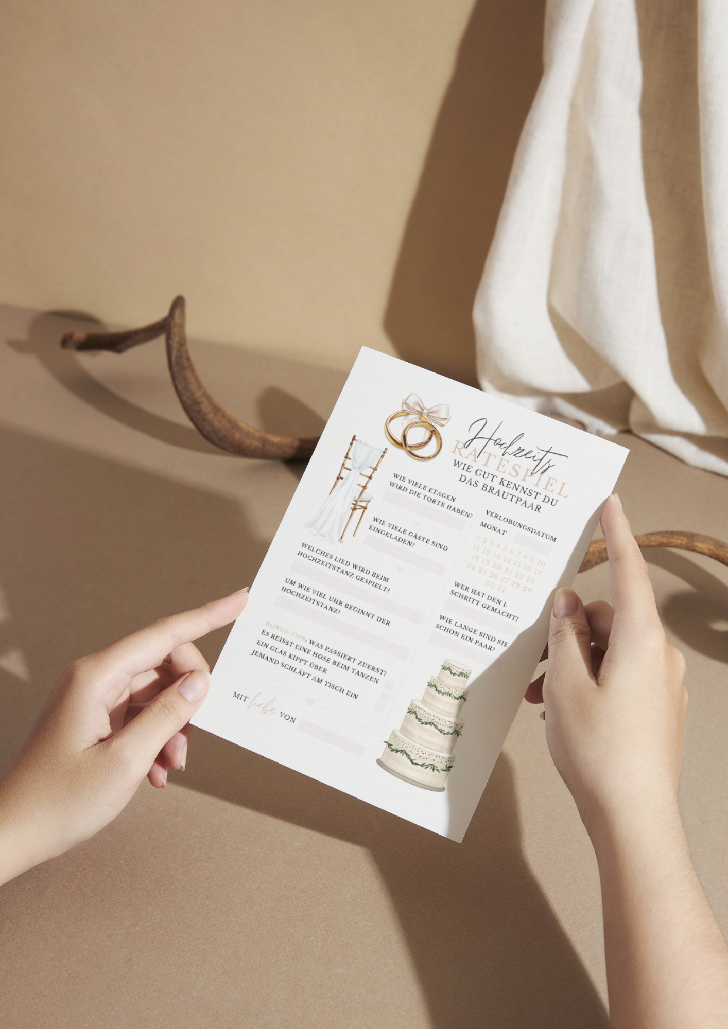 Hochzeitsratespiel Karte mit Brautpaar-Quiz in Boho Farben, stilvoll in Händen gehalten vor warmer Stoffkulisse – elegantes Hochzeitsspiel